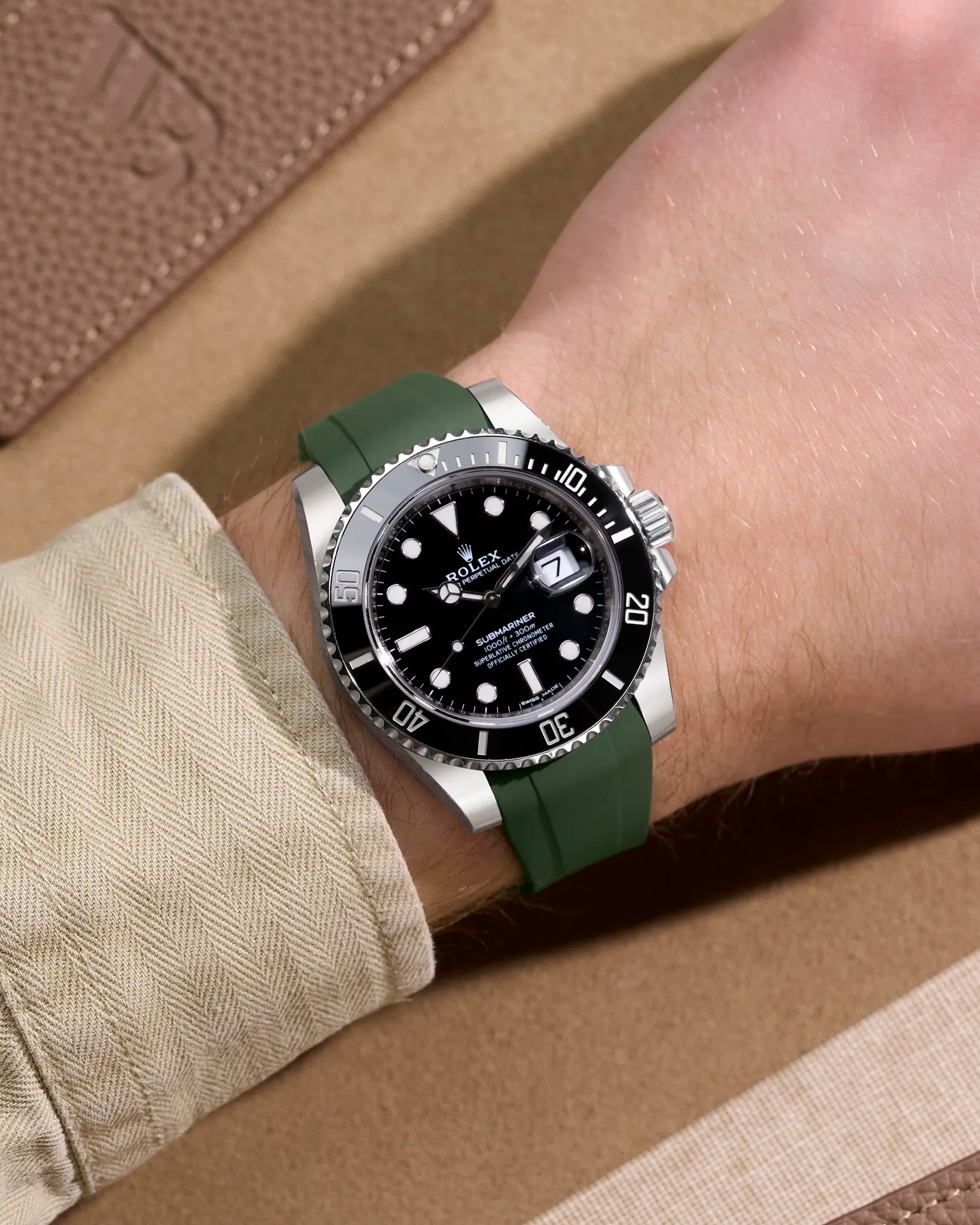 Green rubber strap fitted on Rolex Submariner 114060LN shown on wrist in lifestyle setting