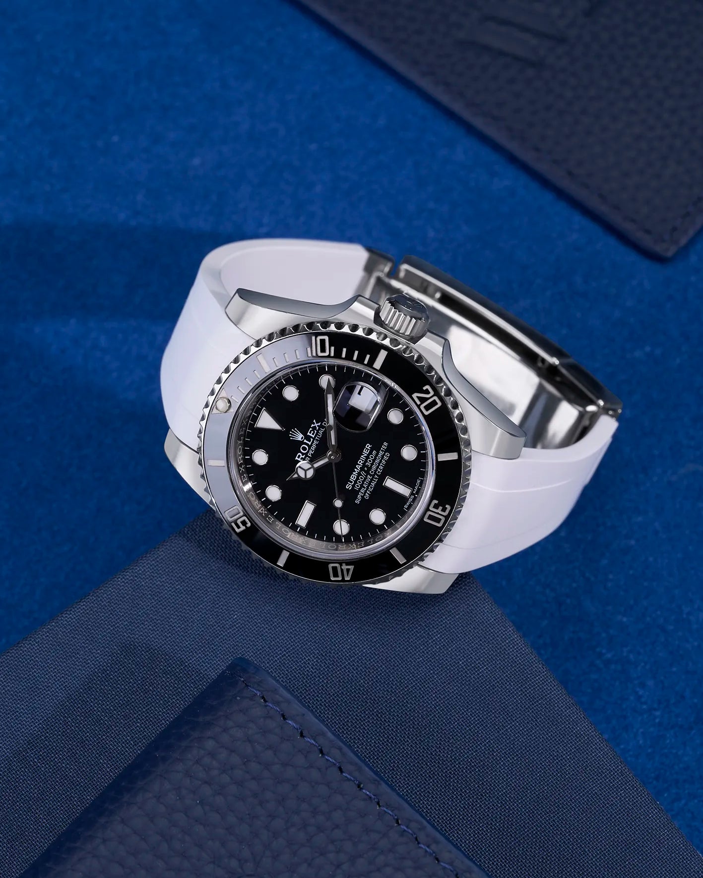 White FKM rubber strap mounted on Rolex Submariner 116610LN watch with original clasp – flatlay on blue textured fabric