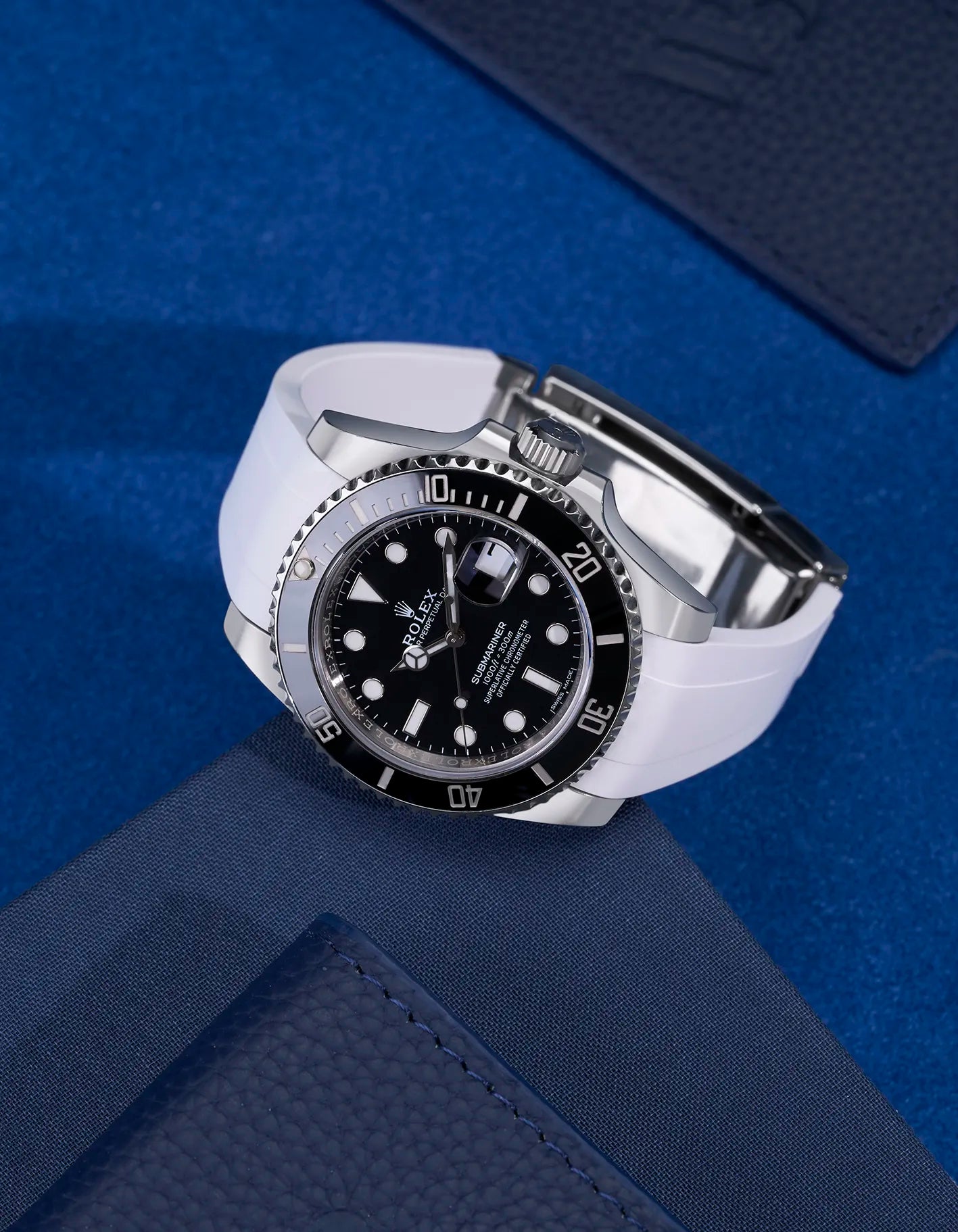White FKM rubber strap mounted on Rolex Submariner 116610LN watch with original clasp – flatlay on blue textured fabric