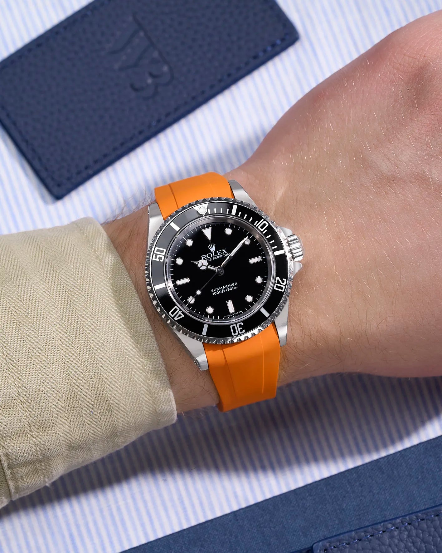 Wrist view of Rolex Submariner 16610/14060 on orange rubber strap with seamless original clasp integration