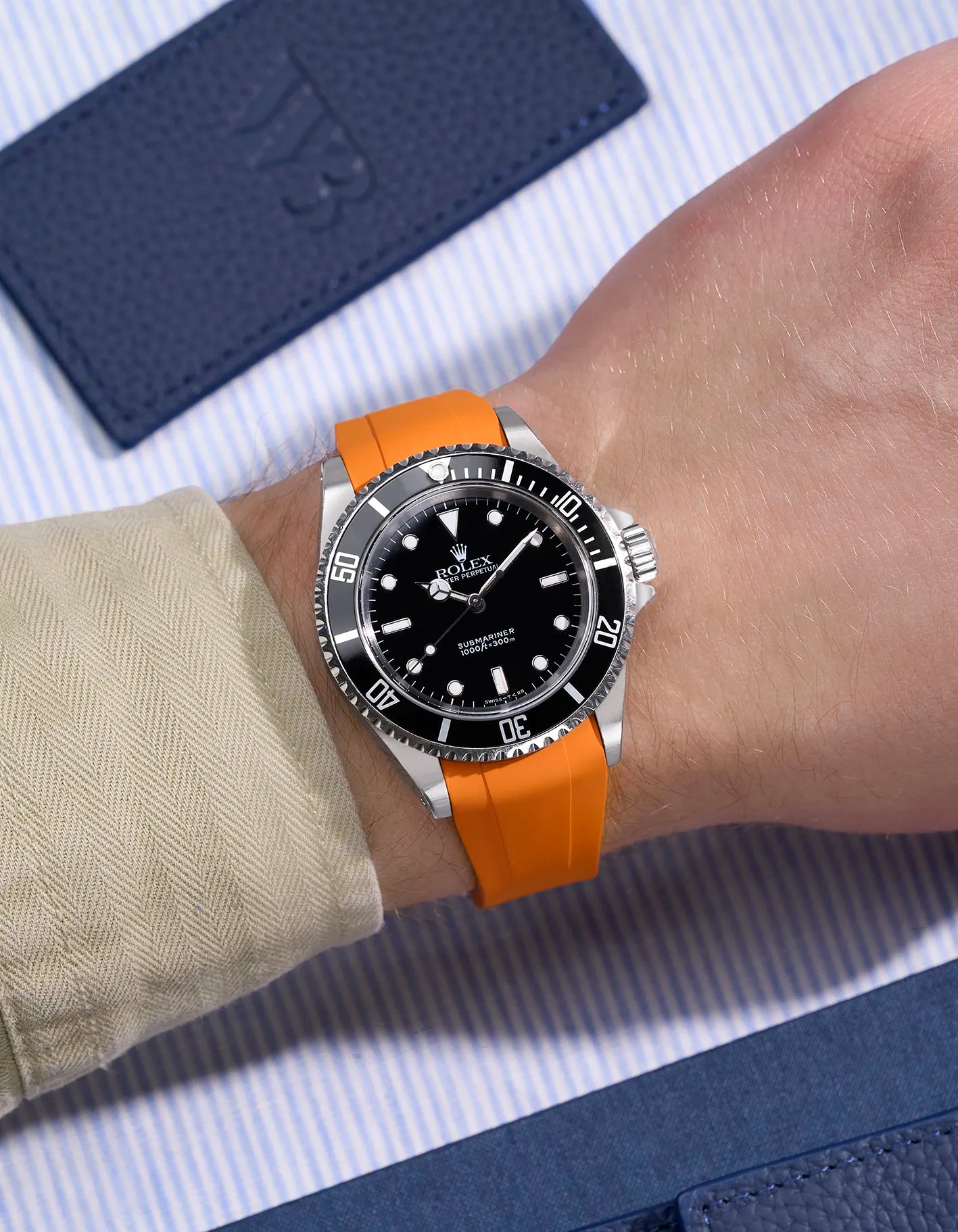 Wrist view of Rolex Submariner 16610/14060 on orange rubber strap with seamless original clasp integration