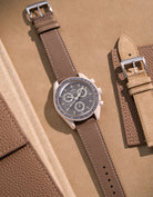 Flat lay of Omega X Swatch Mission on Earth – Desert with Taupe cowhide leather strap, styled with accessories
