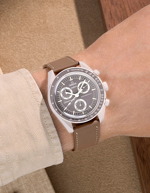 Omega X Swatch Mission on Earth – Desert with Taupe cowhide leather strap worn on wrist – styled shot with beige tones