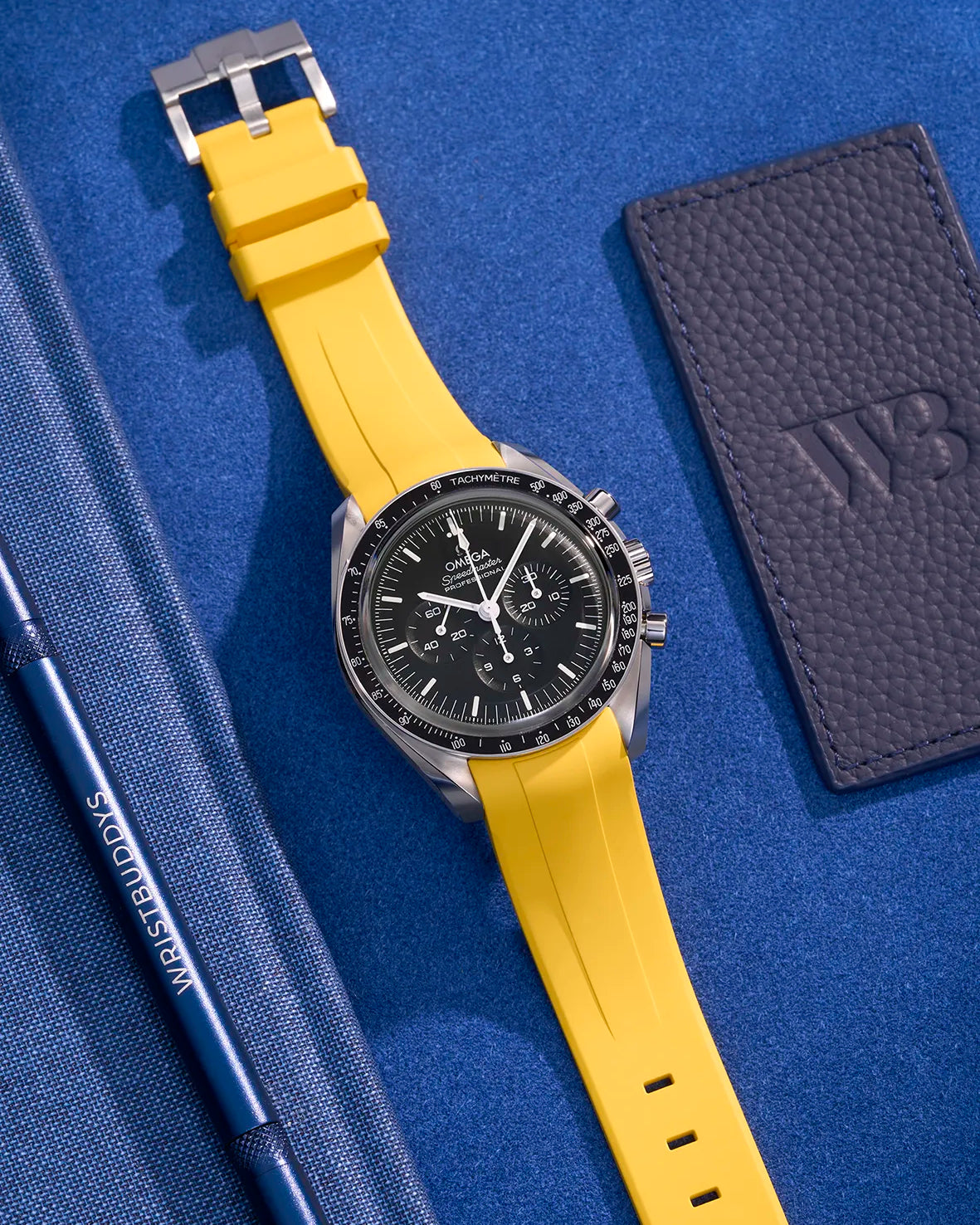 Yellow FKM rubber strap on Omega Speedmaster – flat lay with stainless steel clasp visible