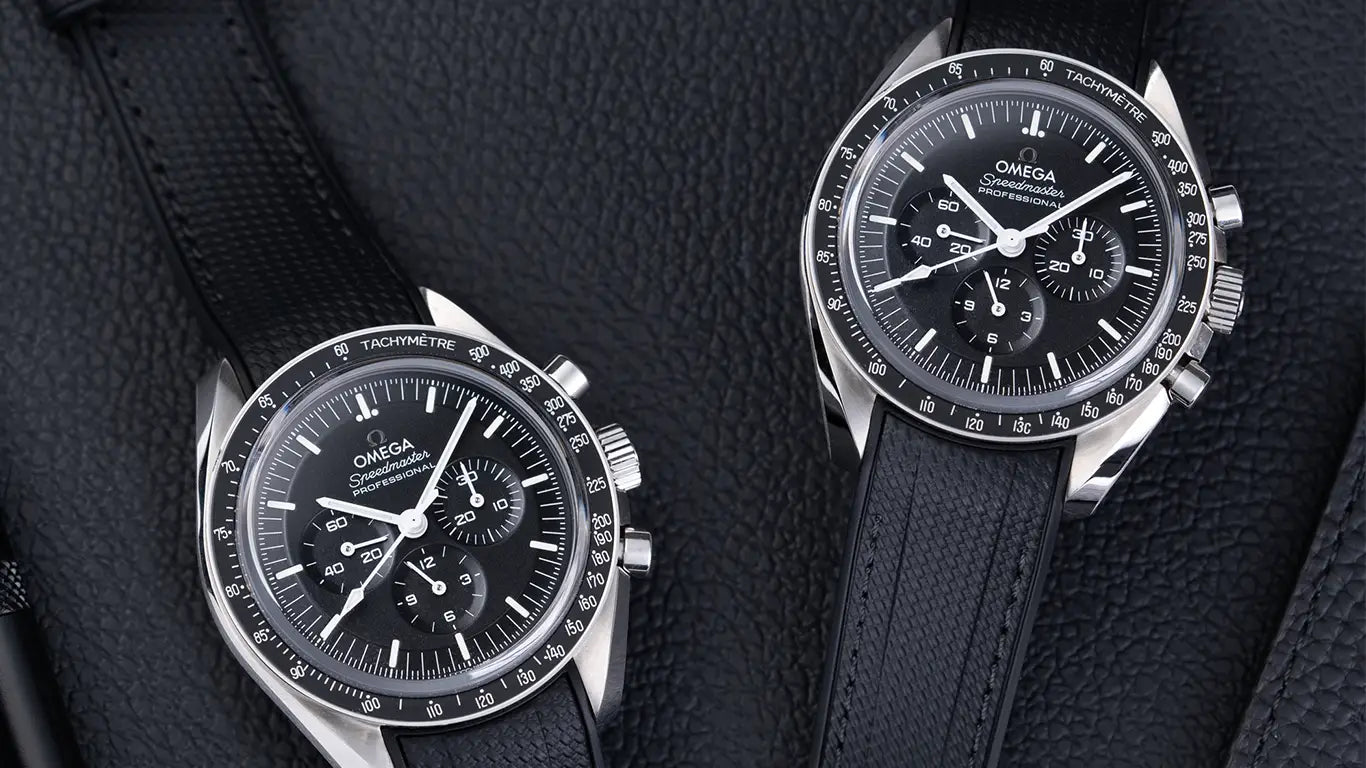 Two Omega Speedmaster watches with black rubber straps on textured black leather background – premium strap upgrade for Speedmaster Moonwatch.