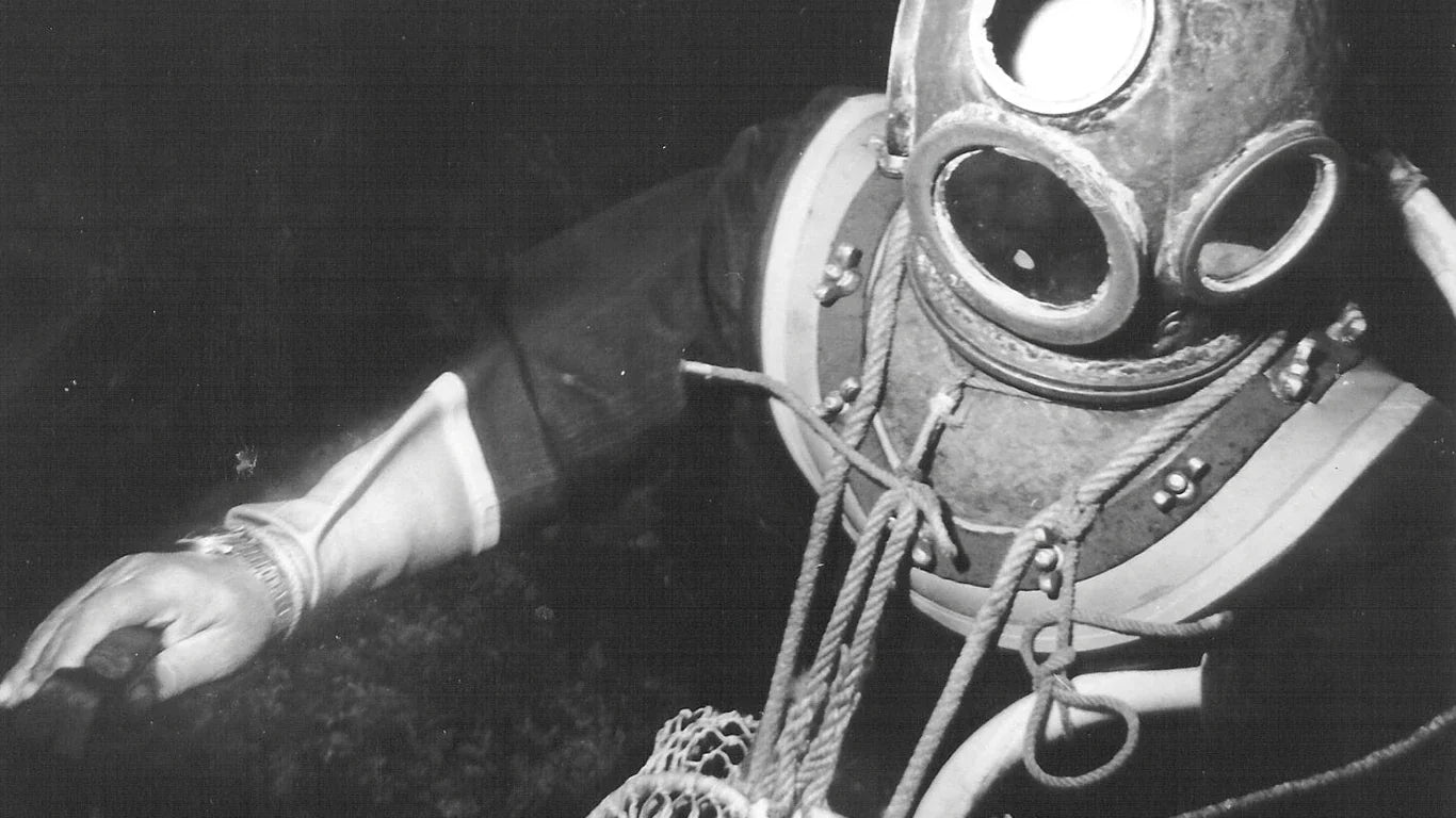 Vintage deep-sea diver wearing a classic diving suit and helmet, sporting an Omega Seamaster – a watch built for extreme underwater conditions.