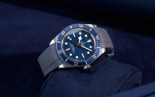 Translation missing: en.Tudor Black Bay watch with blue dial on a matching blue Tudor rubber strap, displayed on a dark blue cushion