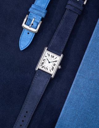 Cartier Tank Must Large watch with Dark Blue Suede Leather strap, lying flat on leather-textured background
