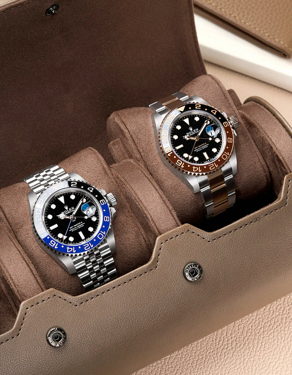Two watches in a brown watch holder with a neutral background