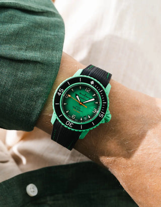 Black Vertech rubber strap with green stitching for Blancpain x Swatch Scuba Fifty Fathoms Indian Ocean – worn on wrist with dark green linen jacket, green dial and black bezel with green case, front angle view