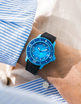 Black Vertech rubber strap for Blancpain x Swatch Scuba Fifty Fathoms Blue Lagoon – worn on wrist with light blue striped shirt, blue dial and blue bezel with light blue case, front angle view