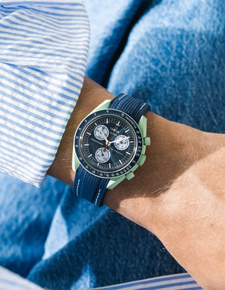 Blue rubber strap with white stitching for OMEGA x Swatch MoonSwatch Mission On Earth, worn on the wrist in a lifestyle photo