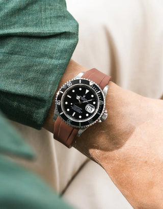 Brown FKM rubber strap integrated for original clasp on Rolex Submariner 16610LN full steel, black ceramic bezel, black dial, straight front-facing wrist shot, smooth brown strap texture, dark green linen shirt sleeve, cream trousers background