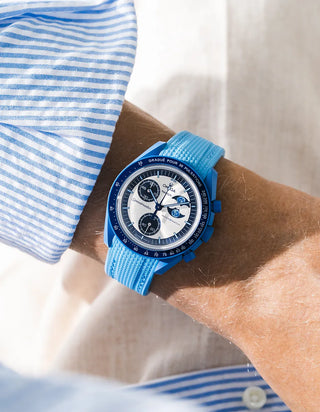 Capri blue rubber strap fitted to an OMEGA x Swatch MoonSwatch Mission to the Super Blue Moonphase watch, worn on the wrist in a lifestyle shot with clothing visible