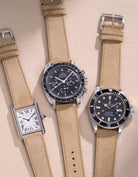 Cartier Tank, Omega Speedmaster and Rolex Submariner watches with beige suede straps.