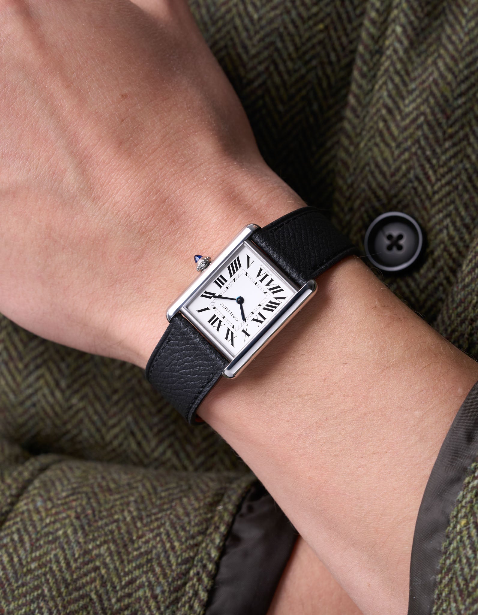 Cartier Tank on a black epsom leather watch strap on a wrist.