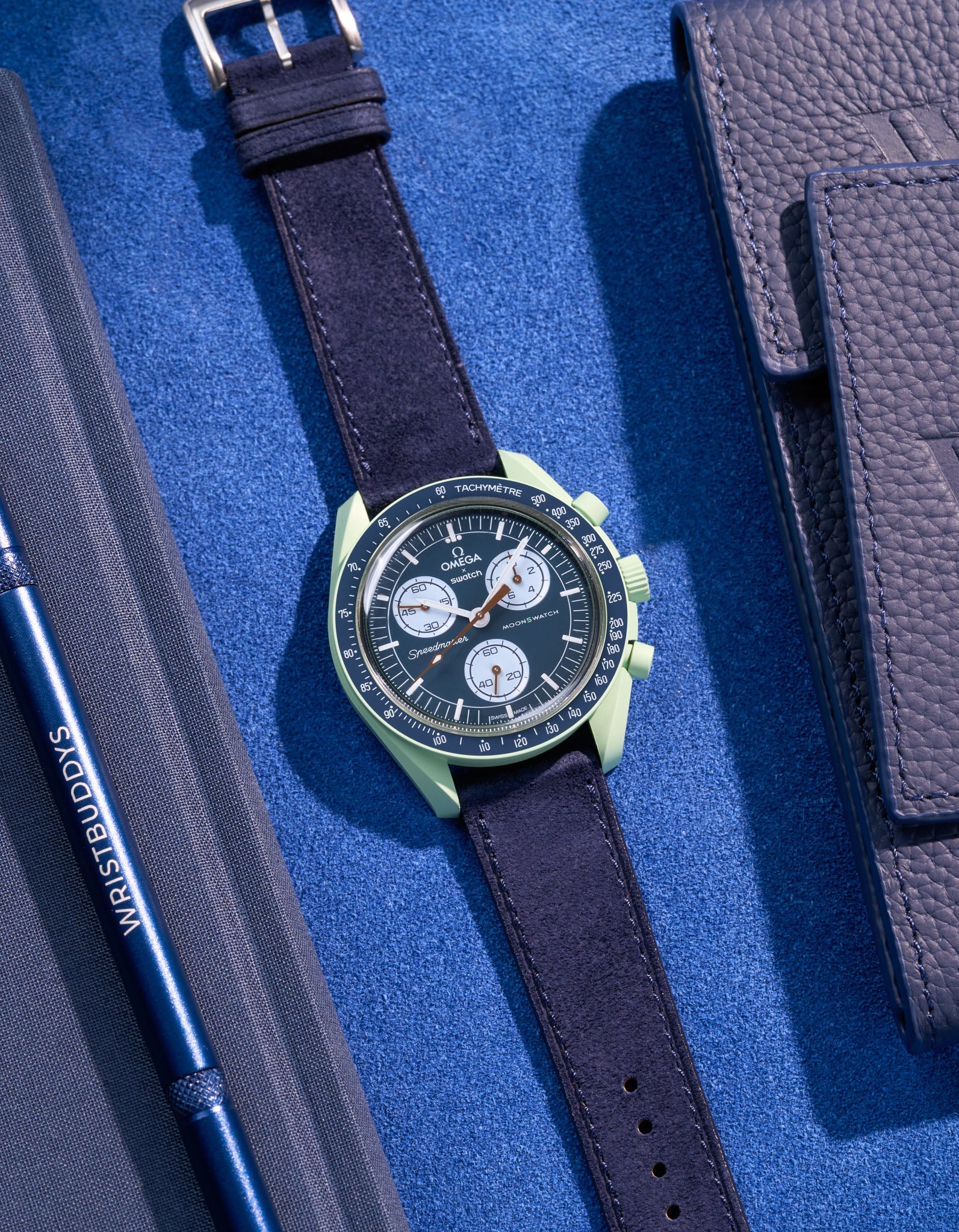 Flat lay Moonswatch Mission on Earth with Dark Blue suede leather strap