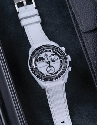 Flat lay of MoonSwatch Mission to EarthPhase with grey rubber strap, watch facing up with clasp visible on a table with black background
