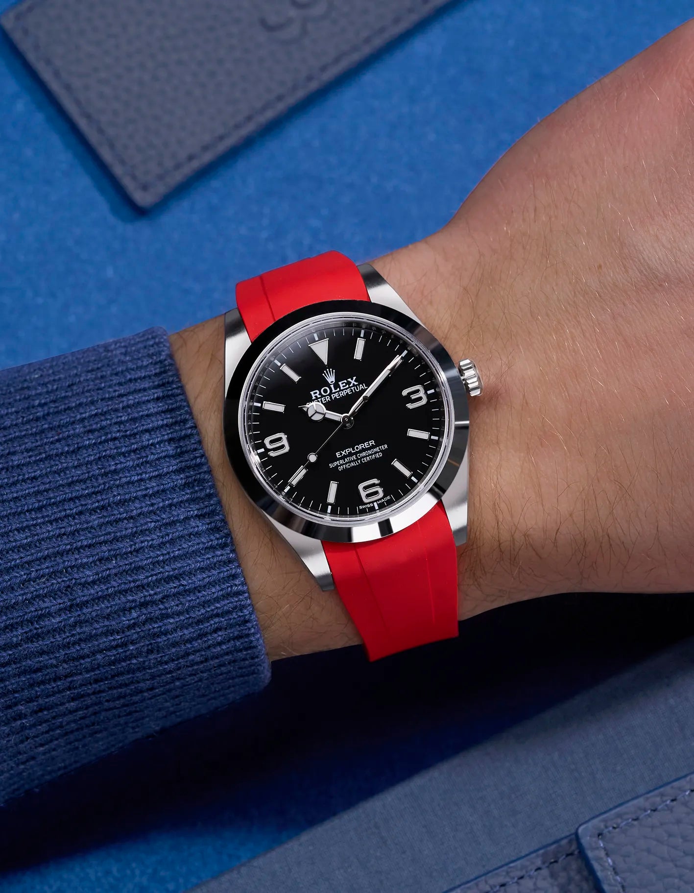 Red integrated rubber strap with original clasp on Rolex Explorer 214270 – wrist shot with navy blue tones