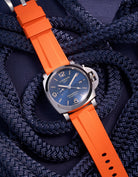 Panerai Luminor GMT Blue Dial with Orange Rubber Strap against Navy Nautical Ropes – Iconic Swiss Made luxury watch in polished stainless steel, paired with a bold 24mm orange rubber uhrenband, perfect for adventurers who value high-visibility design. This Panerai model features a GMT function for dual-time tracking, enhanced by the vibrant orange strap that adds a contemporary twist to traditional luxury, ideal for outdoor activities and nautical-inspired style.