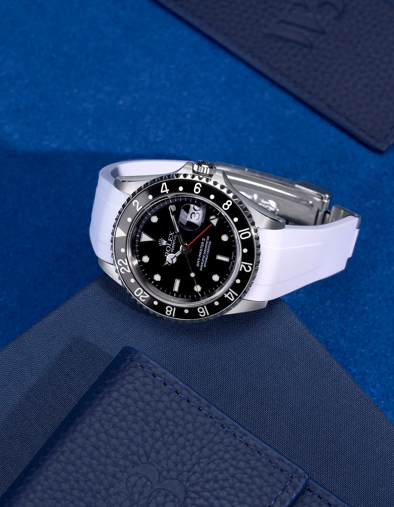 Rolex GMT-Master II 16710 and 16713 with white FKM rubber strap and original clasp – flat lay on blue background