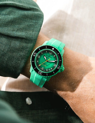 Green Vertech rubber strap for Blancpain x Swatch Scuba Fifty Fathoms Indian Ocean – worn on wrist with dark green linen jacket, green dial and black bezel with green case, side angle view