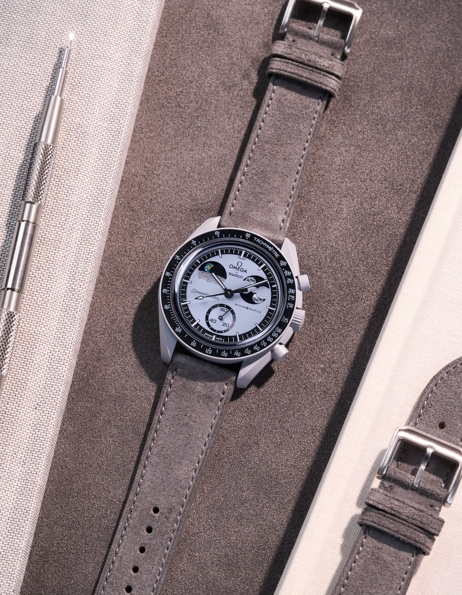 Flat lay Moonswatch Mission to Earthphase with Grey suede leather strap