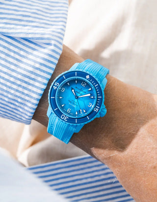 Lagoon blue Vertech rubber strap for Blancpain x Swatch Scuba Fifty Fathoms Blue Lagoon – worn on wrist with light blue striped shirt, blue dial and blue bezel with light blue case, side angle view