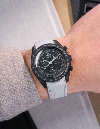 Black Omega X Swatch MoonSwatch Mission to The Moonphase - New Moon with a grey vertech rubber watch strap and a with detailed face on a grey background