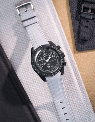 Black Omega X Swatch MoonSwatch Mission to The Moonphase - New Moon with a grey vertech rubber watch strap and a with detailed face on a grey background