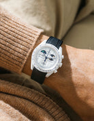 Black rubber strap on Moonswatch Moonshine Gold Cold Moon wrist shot with brown shirt