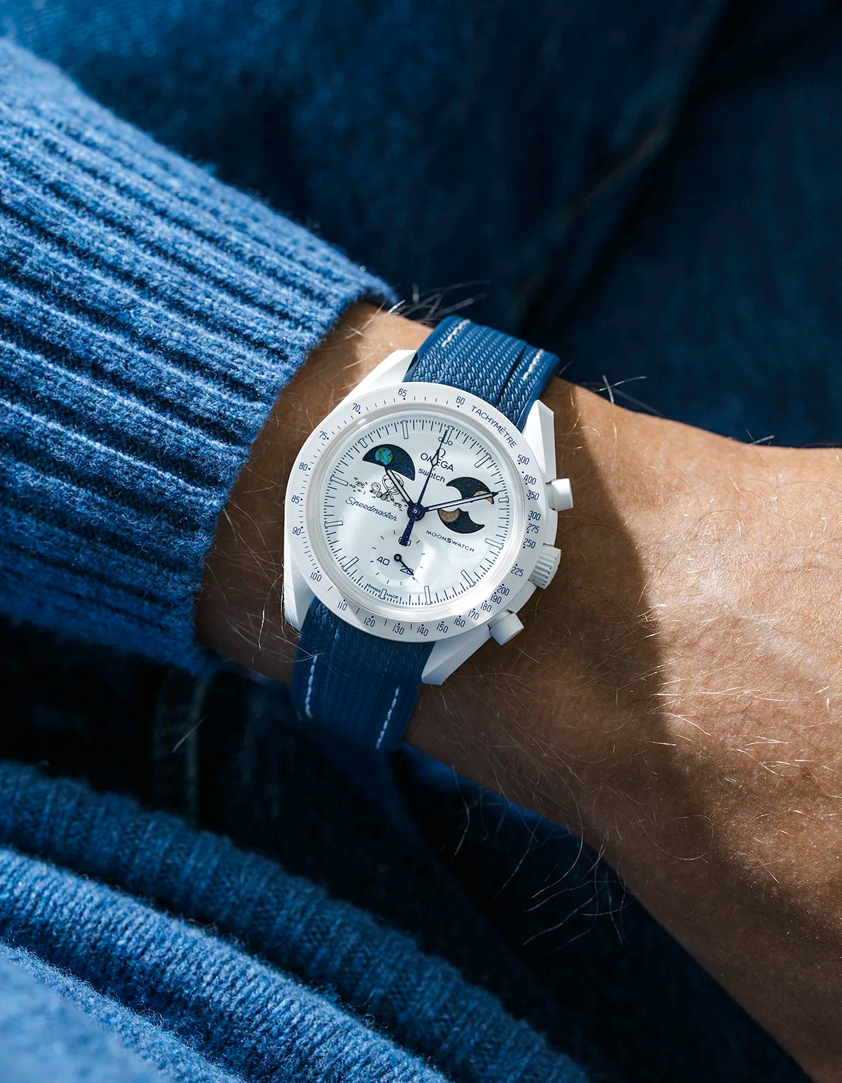 Blue and white rubber strap on Moonswatch Moonshine Gold Cold Moon wrist shot with blue shirt