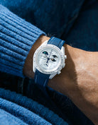 Blue and white rubber strap on Moonswatch Moonshine Gold Cold Moon wrist shot with blue shirt