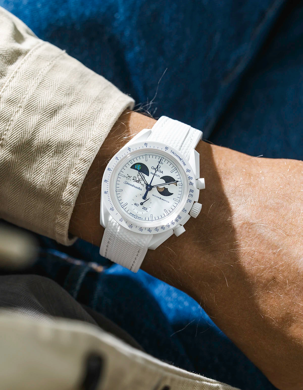 White rubber strap on Moonswatch Moonshine Gold Cold Moon watch wrist shot with beige shirt