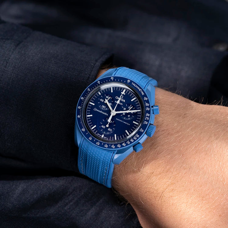 Wrist shot of the Omega x Swatch MoonSwatch Mission to Neptune fitted with a blue rubber strap from Wristbuddys, paired with a matching navy shirt for a cohesive look.