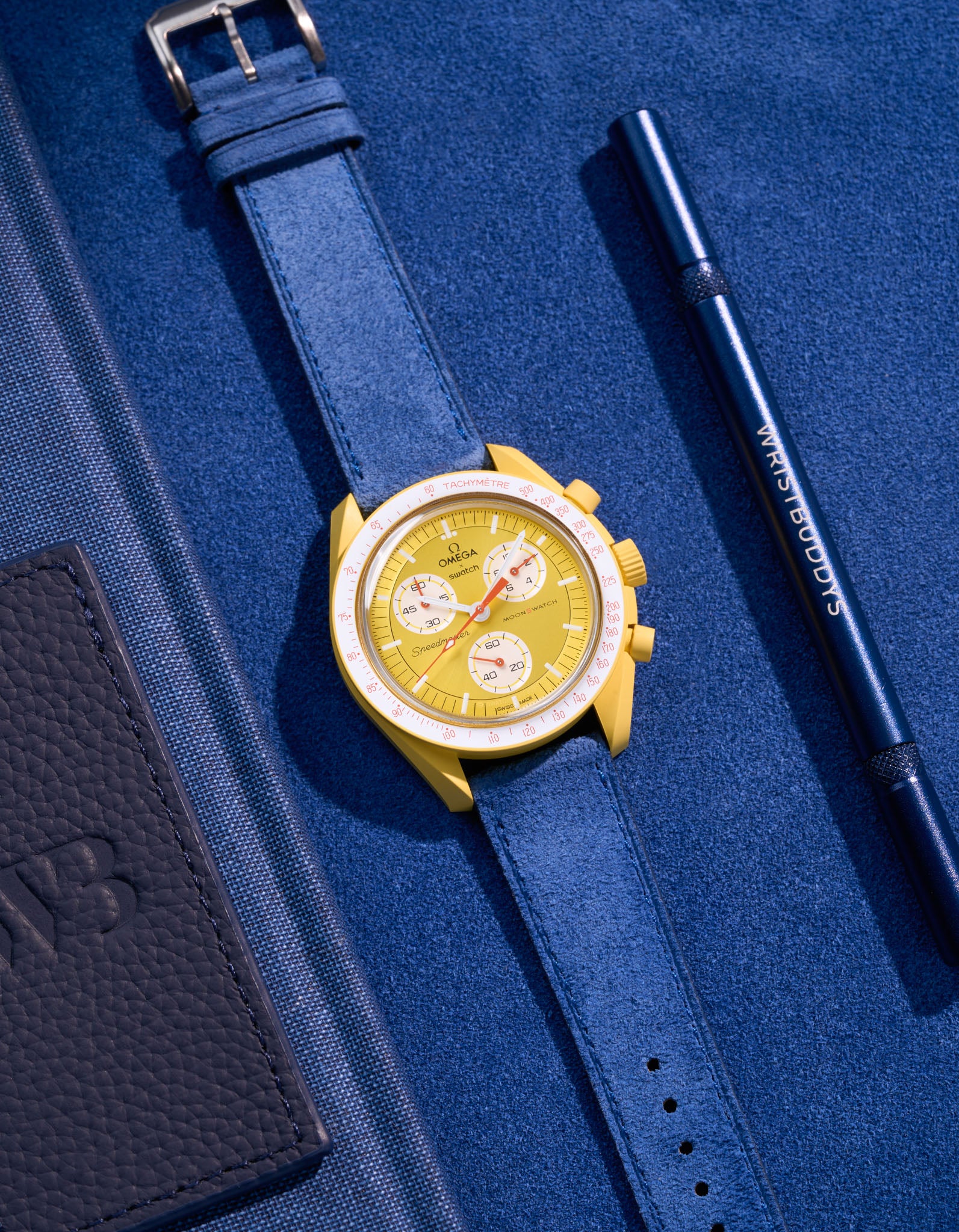Flat lay Moonswatch Mission to the Sun with Ocean Blue suede leather strap