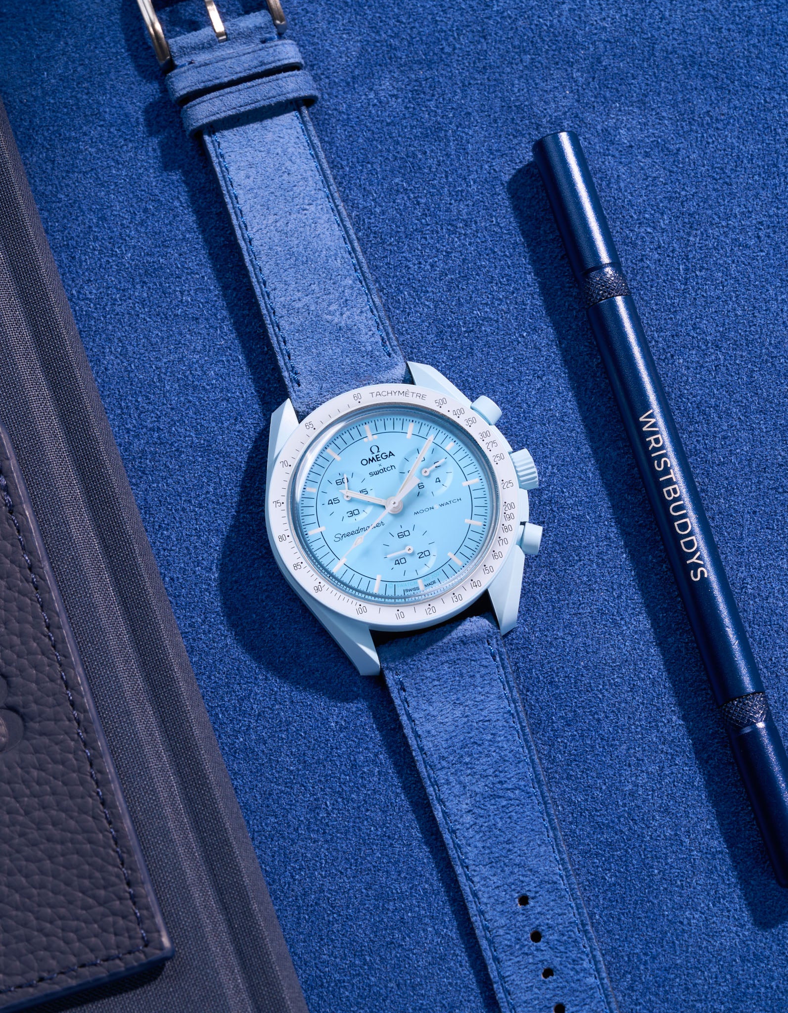 Flat lay Moonswatch Mission to Uranus with Ocean Blue suede leather strap