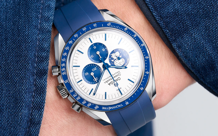 Omega Speedmaster Snoopy on wrist with blue rubber strap hand in pocket wearing a denim jacket