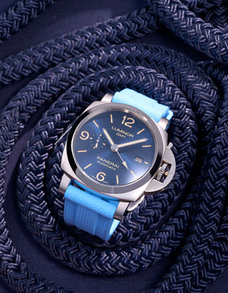 Panerai Luminor GMT Blue Dial with Light Blue Rubber Strap against Navy Ropes – Exklusiv Swiss Made lyxklocka med 44mm polerad rostfri stålboett och 24mm ljusblått gummiband, perfekt för äventyrare som uppskattar både stil och funktionalitet. Denna Panerai GMT-modell erbjuder dubbel tidszon och en distinkt design som gör den idealisk för både nautiska aktiviteter och dagligt bruk. Klockarmbandet ger en fräsch och modern kontrast till den djupblå urtavlan.