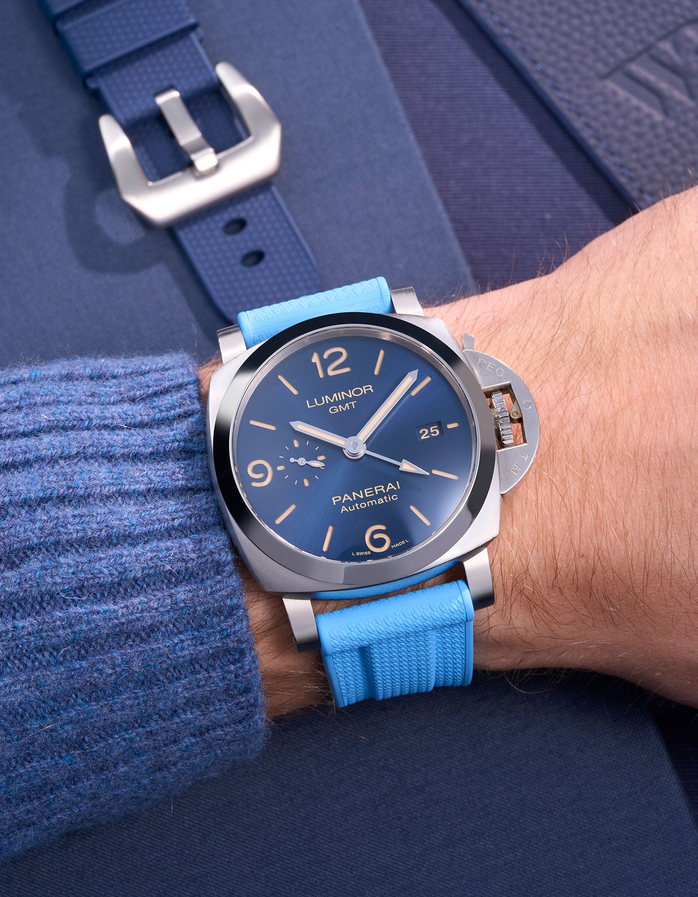 Panerai Luminor GMT Blue Dial with Capri Blue Rubber Strap on Wrist – Swiss Made Panerai med polerad rostfri stålboett och ett färgstarkt ljusblått 24mm gummiband, idealiskt för utomhusäventyr och stilmedvetna bärare. Klockan erbjuder GMT-funktion för dubbel tidszon, vilket gör den praktisk för resande och affärsresenärer. Det ljusblå armbandet tillför en ungdomlig och modern touch till Panerais klassiska design.