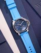 Panerai Luminor GMT Blue Dial Stainless Steel med Capri Blue Rubber Strap – Lyxig, sportig klocka med Swiss Made 44mm boett och ett 24mm ersättningsband i ljusblått gummi. Perfekt för den sofistikerade gentlemannen som söker både stil och hållbarhet. Detta ljusblå klockarmband tillför en elegant men avslappnad stil som kombinerar italiensk design med schweizisk precision, lämplig för både affärs- och fritidsanvändning.