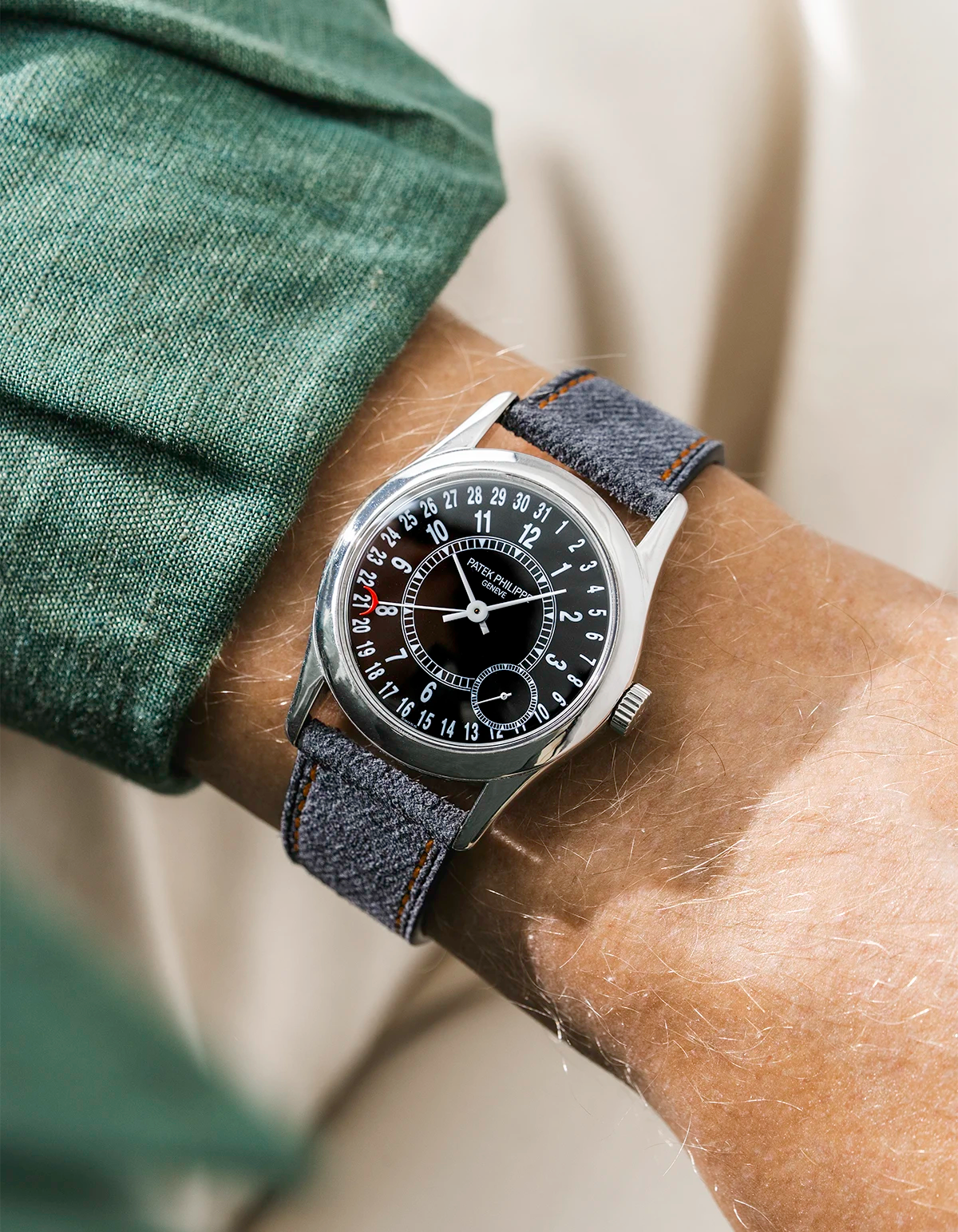 Patek Calatrava on a black denim leather watch strap from Wristbuddys on a persons wrist wearing a green shirt