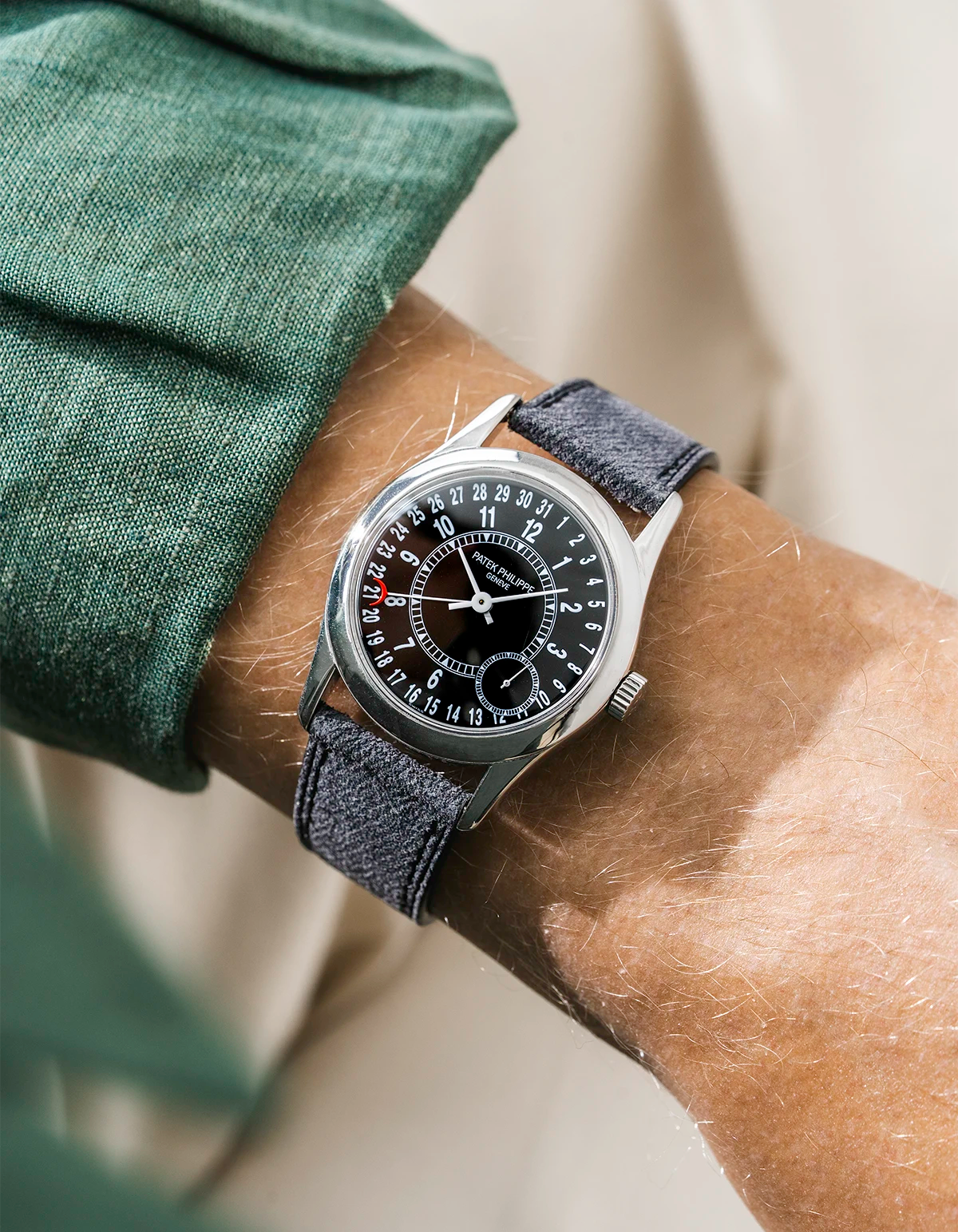 Patek Calatrava on a black denim leather watch strap from Wristbuddys on a persons wrist wearing a green shirt