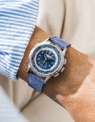 Patek Worldtimer on a blue denim leather watch strap from Wristbuddys on a persons wrist wearing a blue striped shirt