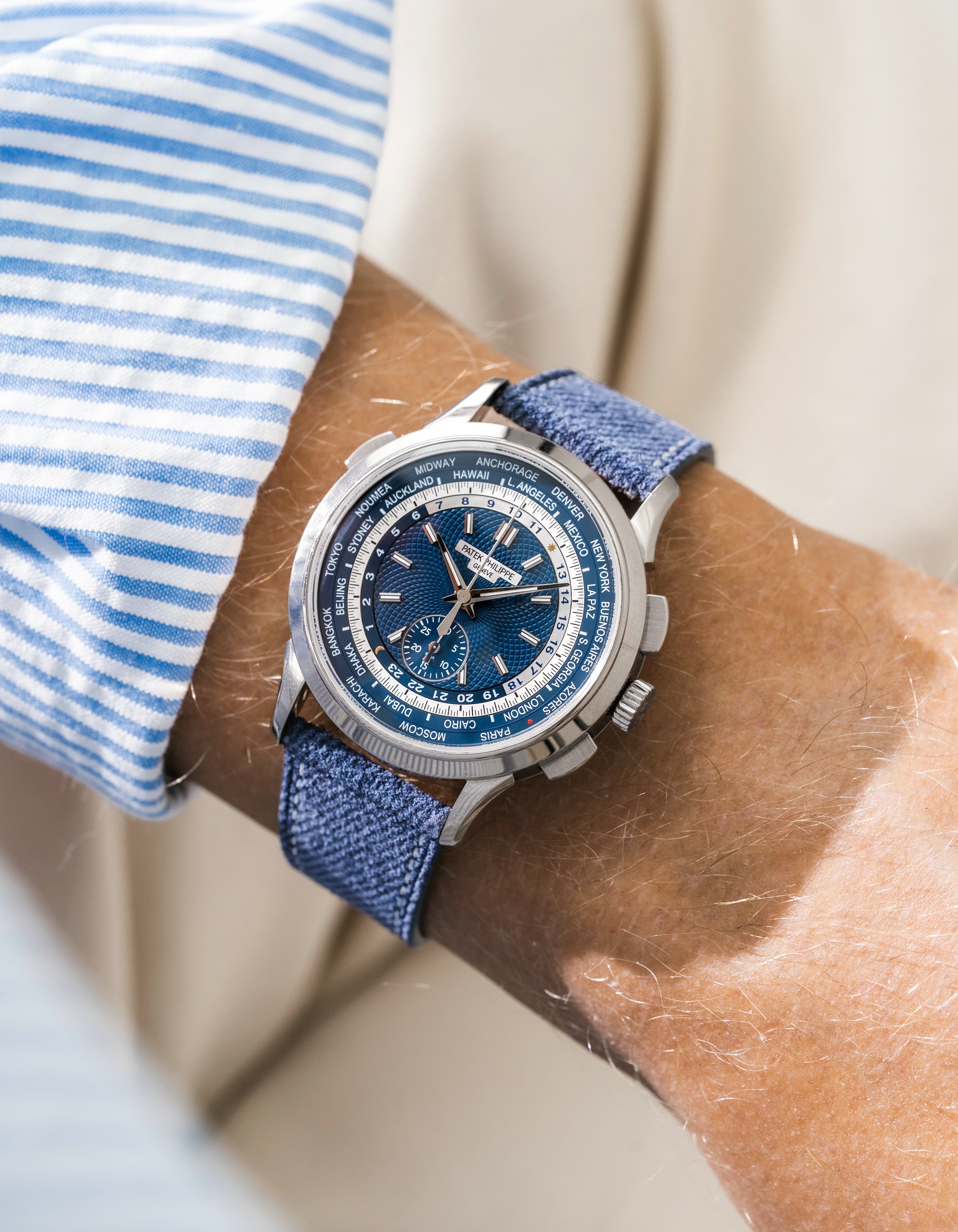 Patek Worldtimer on a blue denim leather watch strap from Wristbuddys on a persons wrist wearing a blue striped shirt