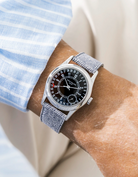 Patek Calatrava on a light grey denim leather watch strap from Wristbuddys on a persons wrist wearing a blue striped shirt