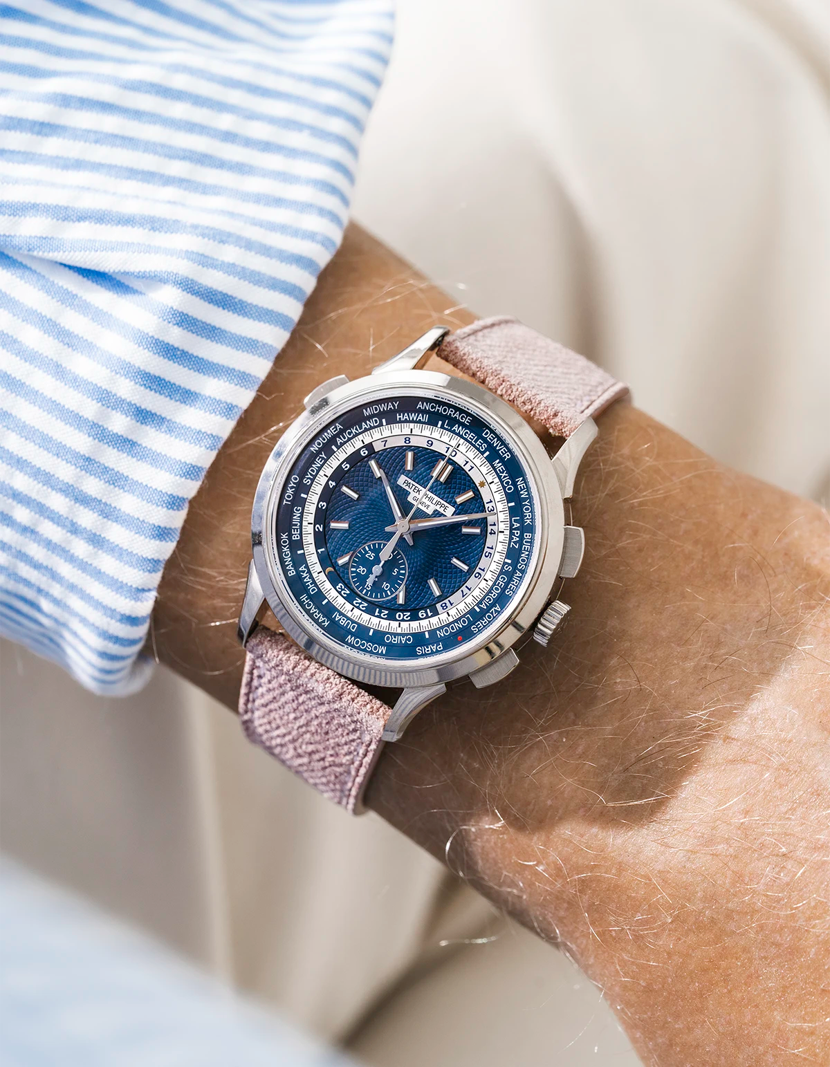 Patek Worldtimer on a pink denim leather watch strap from Wristbuddys on a persons wrist wearing a blue striped shirt