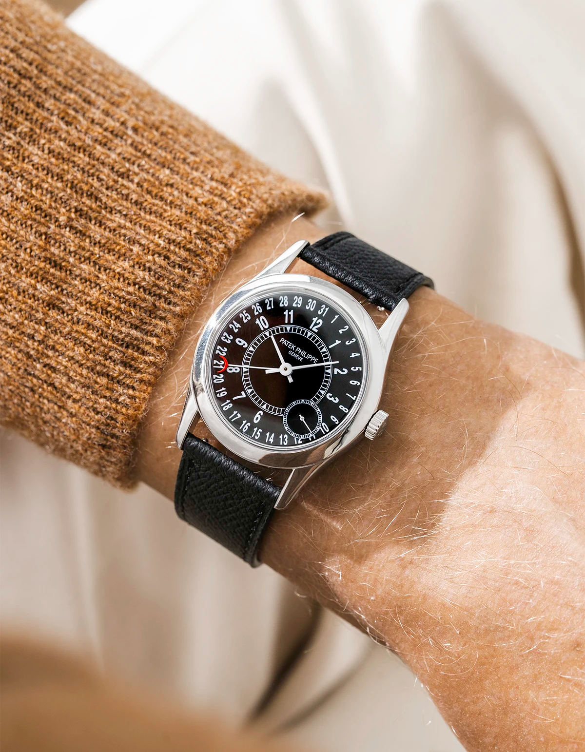 Patek Calatracva on a black epsom leather strap from Wristbuddys on a persons wrist with a beige/brown shirt
