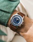 Patek Worldtimer with a blue face and brown suede leather watch strap from wristbuddys on a person's wrist.