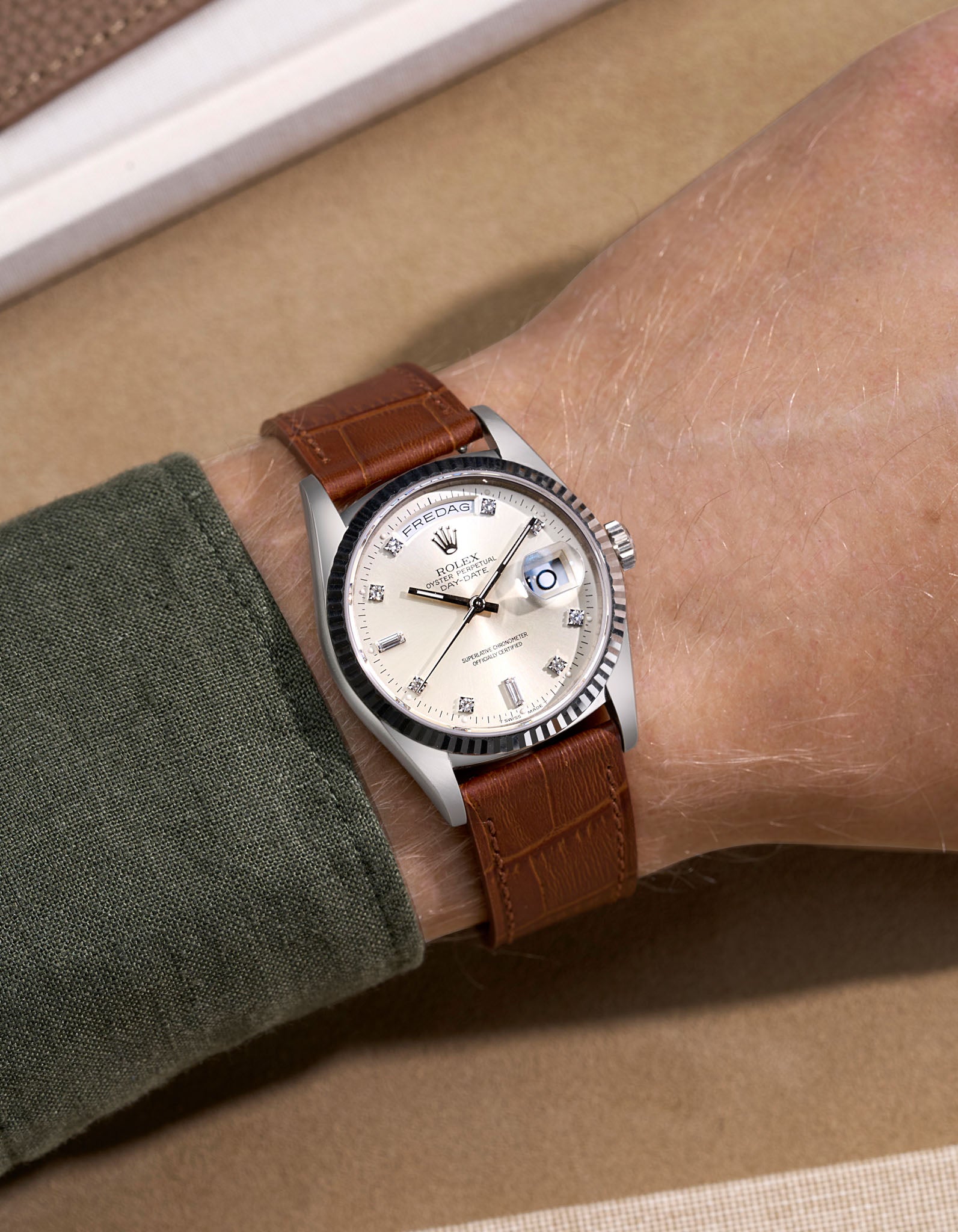 Rolex Daydate with diamond indexes watch with a brown alligator leather strap on a beige background